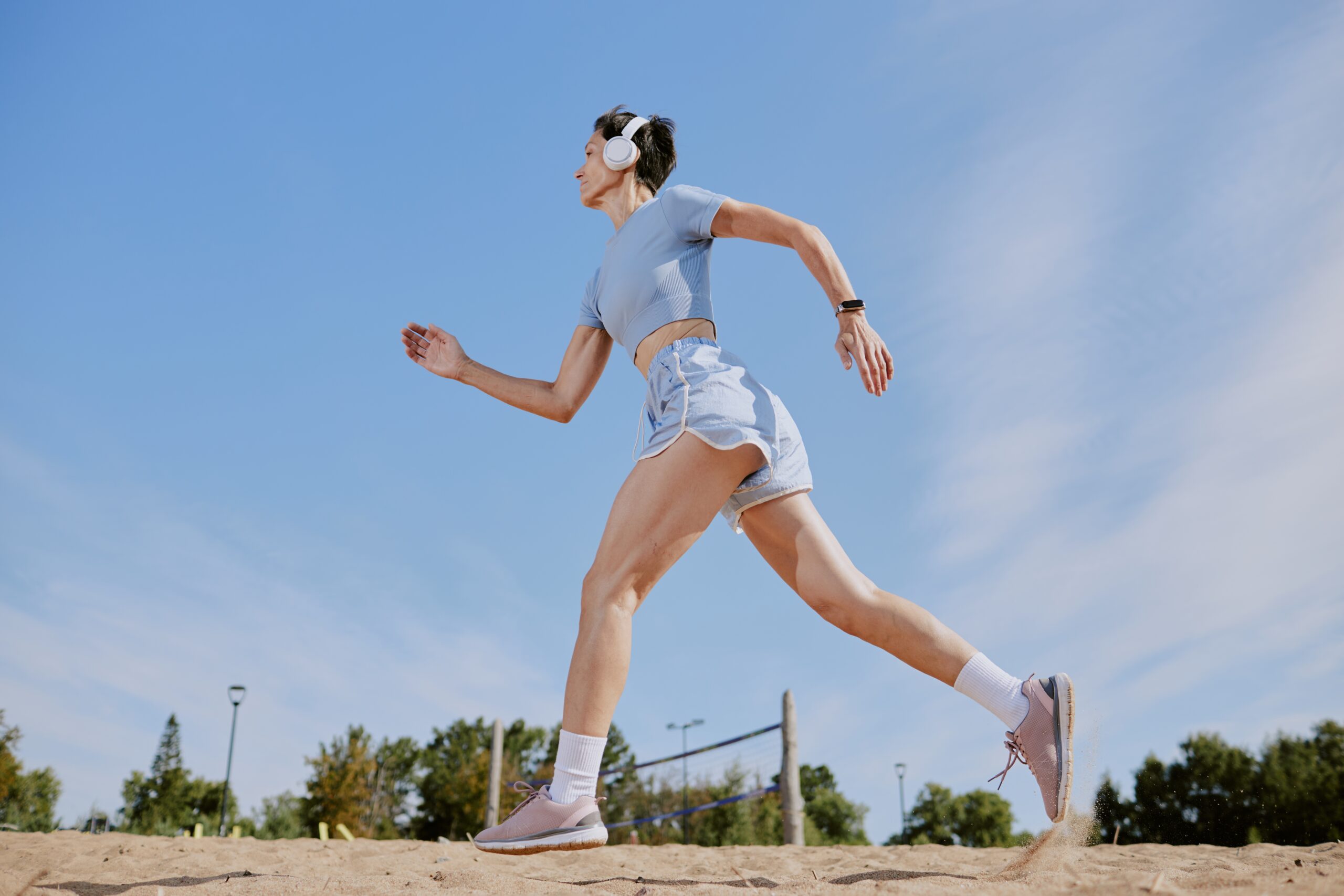 Low angle shot of senior woman jogging and listening to music via headphones