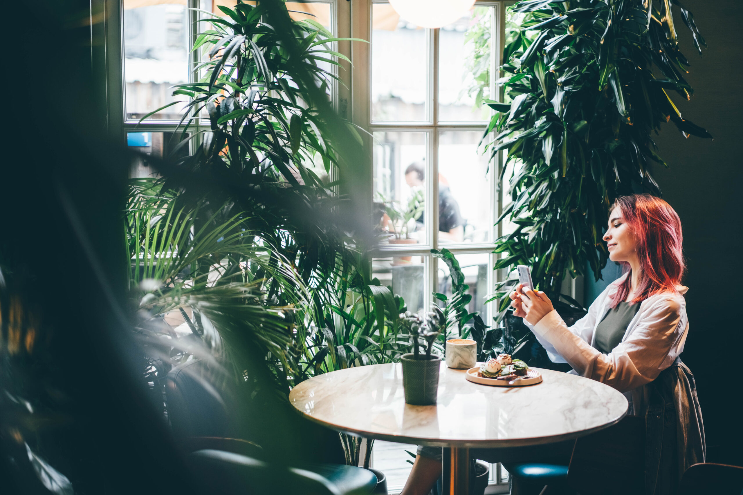 Woman using mobile phone during rest in coffee shop.